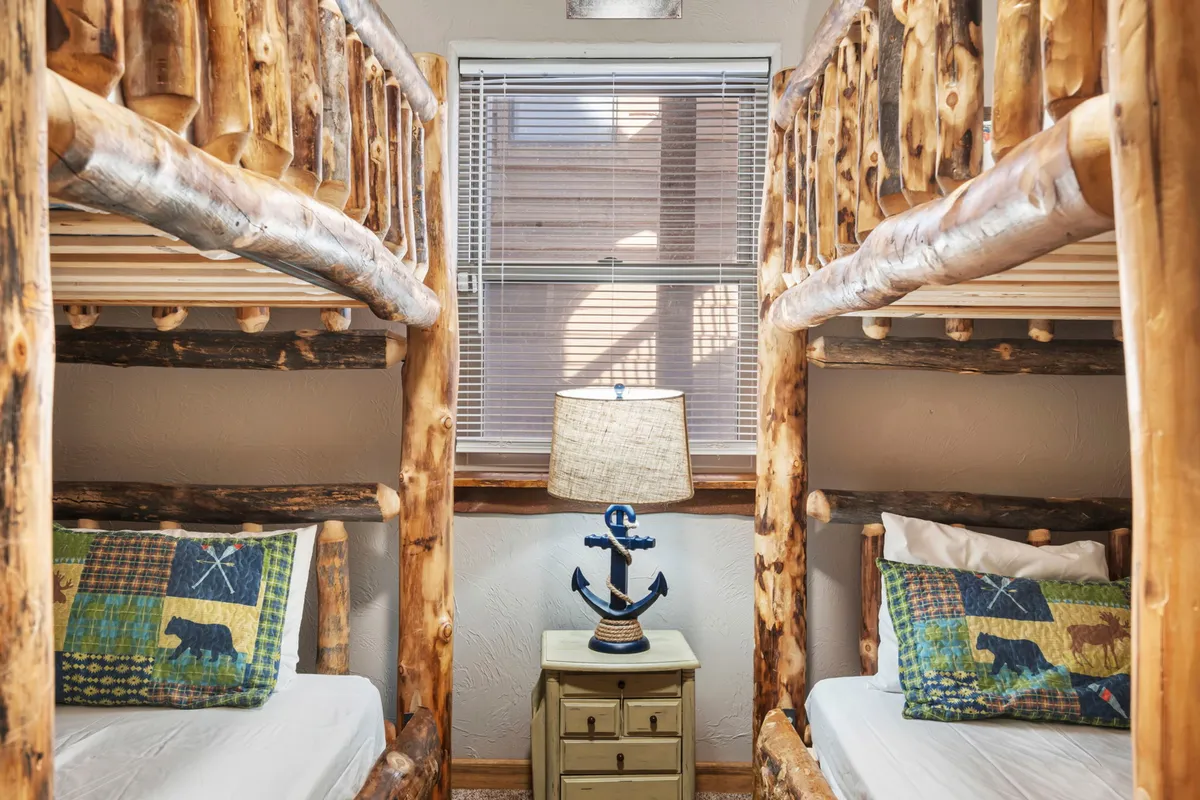 This cheerful room contains a set of bunk beds with decorative pillows and a soft lamp, creating a playful yet comfortable sleeping environment ideal for kids or additional guests.