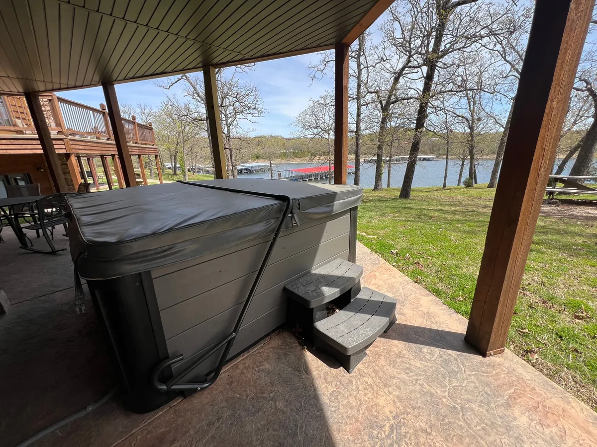 This image captures a private hot tub on a deck with views of the lake and surrounding trees. The deck area offers ample space for socializing or relaxing, and the tranquil water view sets the scene for unwinding after a day of group activities.