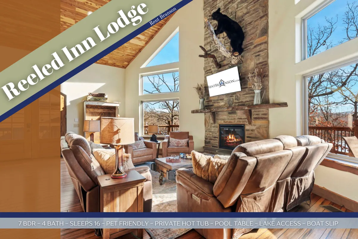 A spacious interior featuring a striking stone fireplace, expansive windows offering tranquil lake views, plush seating arranged for conversation, and a pool table anchoring the gathering area. A touch of lodge character is added by taxidermy decor, while the comfortable setup invites relaxation and togetherness.