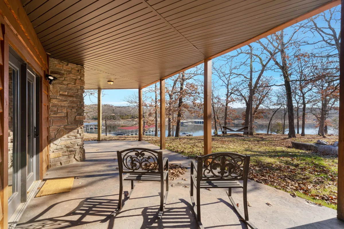 A tranquil patio setup overlooking the lake, with comfortable outdoor seating surrounded by trees. The ambiance is calming, ideal for spending time with pets or simply enjoying fresh air and nature.