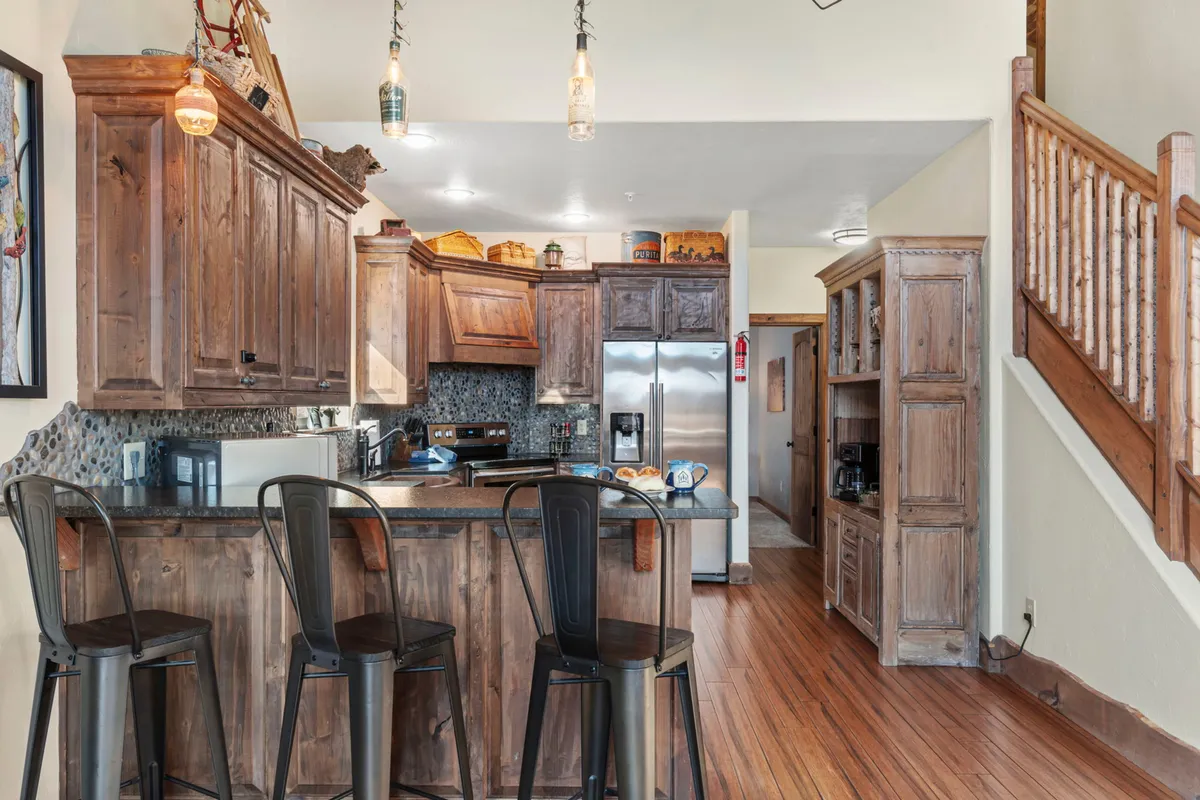 A modern, fully equipped kitchen with a central island, stainless steel appliances, warm wooden cabinetry, and hanging pendant lights. The open layout encourages conversation and activity, inviting guests to cook, socialize, and entertain.
